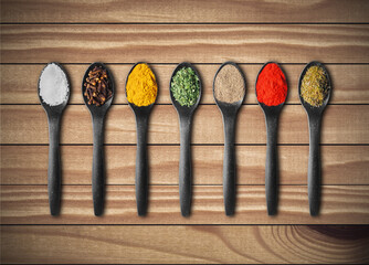 Various spices in spoons on wooden table
