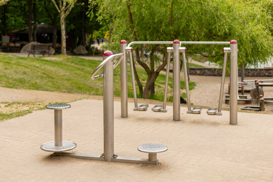 A set of outdoor fitness equipment located in a park offers various workout stations amid lush trees and pathways. This area encourages locals to engage in physical activity