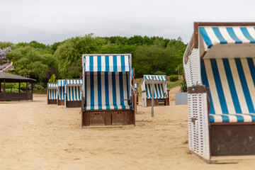 Multiple beach chairs with blue and white stripes are arranged on the sandy shore of a coastal...