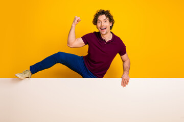 Energetic young man in casual fashionwear enthusiastically posing against a vivid yellow background
