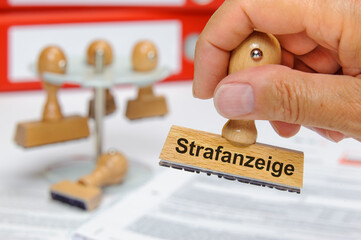 Ein Holzstempel ist beschriftet mit dem Aufdruck Strafanzeige