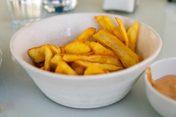 Thick-cut golden French fries served in a white ceramic bowl, ideal as a side dish or fast food snack.