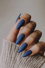 Modern elegance with a matte finish: Hands with long, pointed nails, painted in a deep blue shade with a sophisticated matte effect. Ideal for beauty, fashion and contemporary nail art themes.