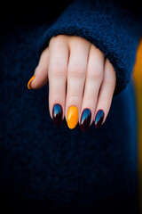 Modern autumn manicure: Hands with nails painted in deep shades of black and mustard yellow, creating an elegant contrast. Ideal for beauty themes, nail art trends, autumn and sophistication.