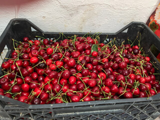 Ripe red cherries in black plastic crate. Fresh berries at market or store.