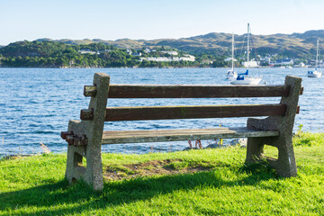 Empty bench overlooking scenic bay with boats in Kyleakin, Isle of Skye, Scottish Highlands