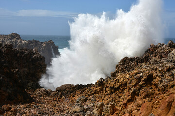 big waves breaking at a cliff in the western Algarve of Portugal