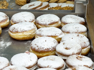 Powdered sugar donuts on baking tray with variety of cookies in background