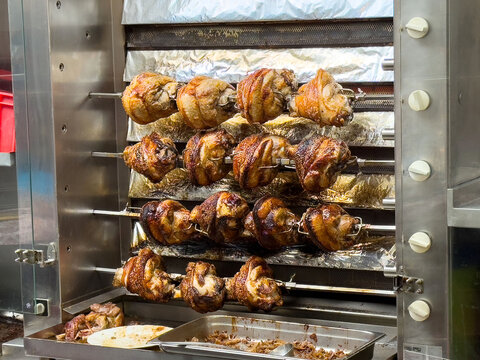 Golden rotisserie chicken on spit in metal grill