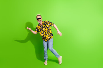 Smiling man in vibrant printed shirt posing on bright green background, showing style and charisma...