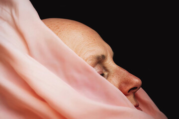 Naklejka premium Soft silk drapes around serene face in a contemplative setting