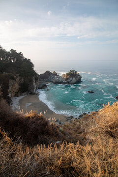 Iconic McWay Falls Cascading onto a Secluded Beach in a Turquoise Cove at Sunset in Big Sur, California