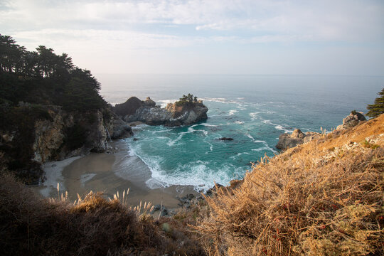 Iconic McWay Falls Cascading onto a Secluded Beach in a Turquoise Cove at Sunset in Big Sur, California