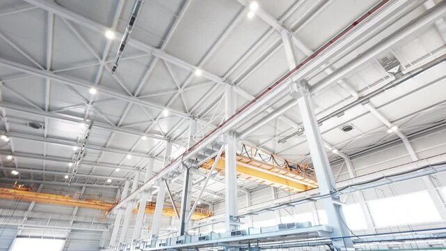 Crane runway girder and metal supporting structures of industrial workshop. Bridge cranes inside hangar. Overhead traveling gantry crane beams on the pillars and truss ceilings of industrial building