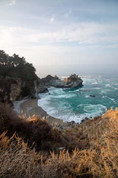 Iconic McWay Falls Cascading onto a Secluded Beach in a Turquoise Cove at Sunset in Big Sur, California