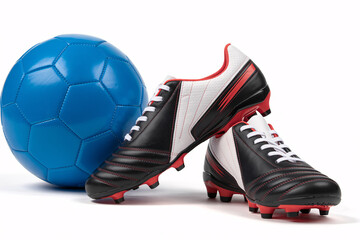 Pair of Black and White Soccer Cleats with Red Accents Beside a Blue Soccer Ball on White Background