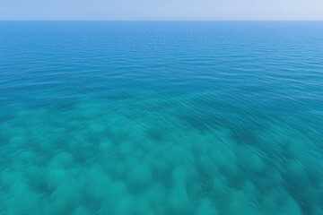 aerial view of the blue ocean surface in a shallow place, the seabed is visible through the water