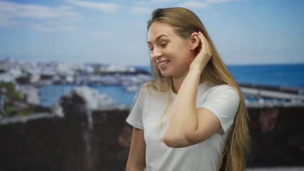 Woman smiling with hand to ear in port setting listening to gossip, adding playful mood with boats...