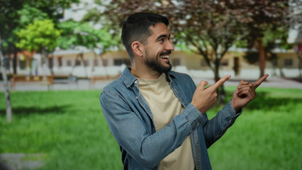 Young man in denim shirt smiling and pointing outdoors in a vibrant green park on a sunny day,...