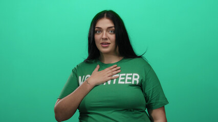 Curvy woman volunteer in green shirt stands over isolated green background wall, embodying...