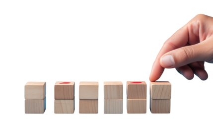 Hand placing a wooden block on a stack of blocks with red markings on some of the blocks in a row