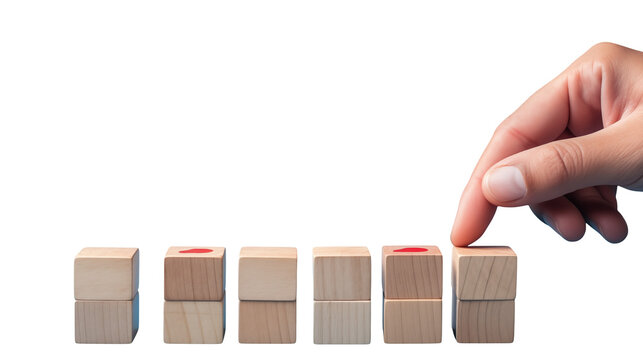 Hand placing a wooden block on a stack of blocks with red markings on some of the blocks in a row