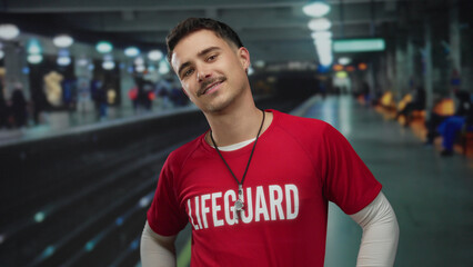 Young hispanic man with mustache and earring wearing lifeguard t-shirt stands confidently at indoor...