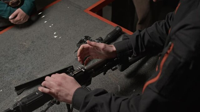 High angle cropped shot of male professional explaining rifle structure to trainee in shooting club