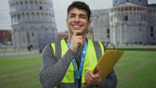 Man places chin on hand to think beside rome cathedral with hispanic outdoor volunteer clipboard portrait and bright smile.