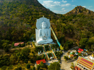 A majestic large sitting Buddha statue meditating amidst lush green hills and natural light. This peaceful place showcases the harmony of sacred architecture and natural beauty. mountain background