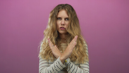 Fototapeta premium Woman arms crossing studio blonde young stop serious pink denial scene conveys clear refusal.