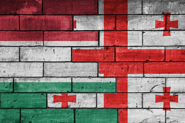 colourful painted big national flag of georgia and flag of hungary on a massive old brick wall background. concept