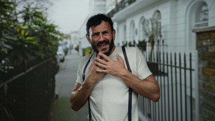 Hispanic man with beard displays anxious emotions on an urban street while surrounded by outdoor...