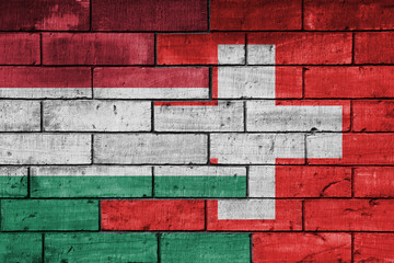 colourful painted big national flag of switzerland and flag of hungary on a massive old brick wall background. concept