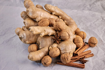 large and beautiful ginger root with walnuts, star anise and cinnamon sticks on a gray background, close-up