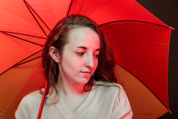 Portrait of a pretty girl under an umbrella in the light of a red lantern