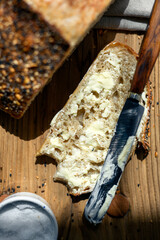 Top view of sliced white sourdough bread with butter and knife close up. Simple breakfast on wooden background