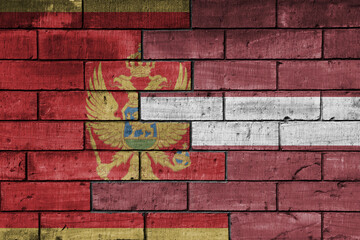 colourful painted big national flag of latvia and flag of montenegro on a massive old brick wall background. concept