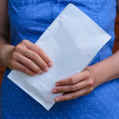 Woman holding white paper pack in her hands. Close-up