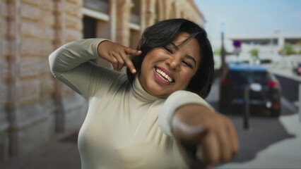 Woman smiling, pointing enthusiastically outdoors in the city, showcasing confidence and positivity...