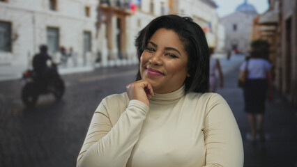 Woman smiling outdoors on city street in an urban setting, featuring a young, plus size, hispanic, latin, female with thoughtful expression.