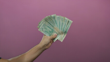 Caucasian man holding united arab emirates dirham banknotes with a pink background offers an...