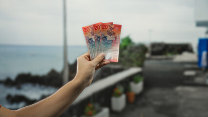 Man holding swiss banknotes outdoors on a city street, illustrating financial themes with a...