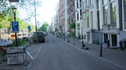 Blurred street scene captures charming canals and classic architecture in amsterdam, netherlands, with a focus on bokeh effect and serene urban landscape.