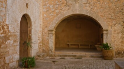 Blurred view of an ancient cloister with stone arches and rustic walls, highlighting classical architecture and tranquility, ideal for history or heritage themes.