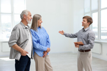Smiling real estate agent showing apartment to couple indoors