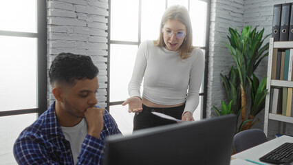 Woman scolding man in modern office setting with bright windows and plants, showcasing workplace dynamics between employees in an interior business environment.