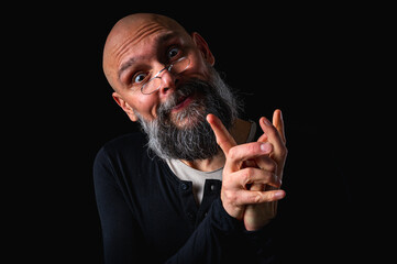 Portrait of a cunning-looking bald man with gray beard and glasses, clasping hands. Dark background. Mischievous or scheming expression. Concept of plotting, sarcasm, or ironic humor