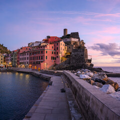 Fishing village Vernazza in Cinque Terre at dusk, with multicolored houses and calm sea view. Picturesque Italian harbor town captured in evening coastal light