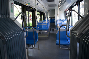 Fototapeta premium Interior of a modern city bus featuring empty blue seats and spacious layout with natural light streaming in